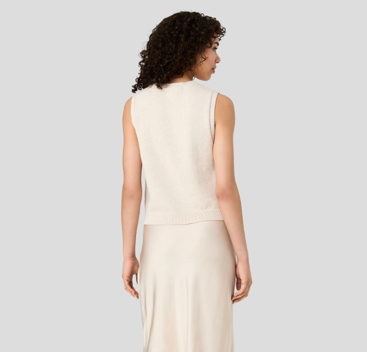 A model shown from the back wearing a sleeveless cream knit vest over a matching cream skirt, set against a solid light gray background.