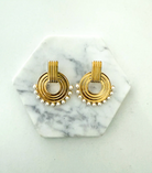 Gold hoop earrings with pearl accents on a marble surface