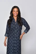A woman modeling a dark navy blue long-sleeve button-up shirt dress with a white geometric pattern, set against a plain light gray background.