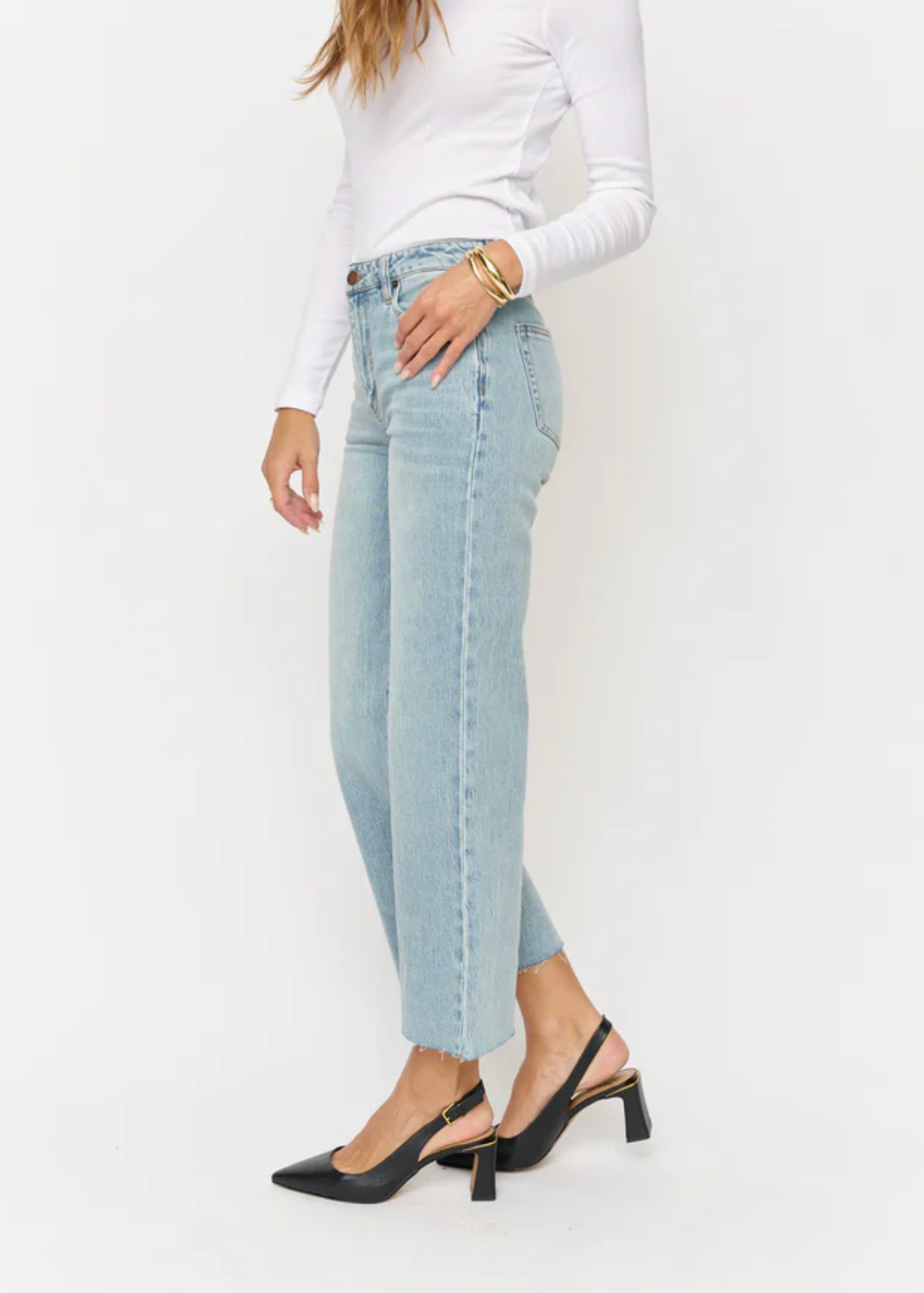 Person wearing light blue jeans and a white long-sleeve top on a white background