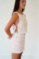 Woman wearing a striped dress with cut-out sides against a plain background