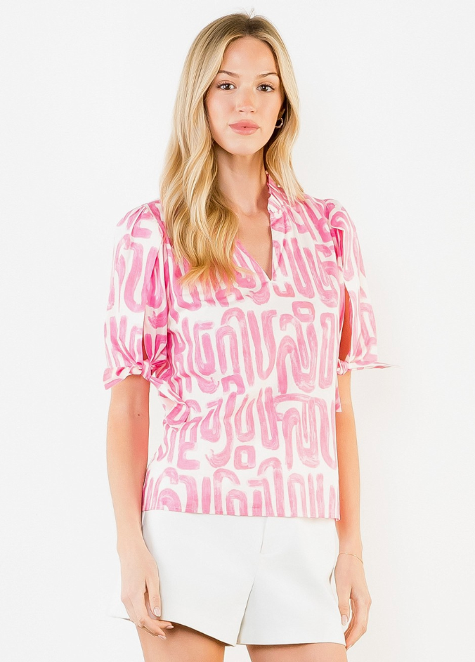 Woman wearing a pink patterned blouse and white shorts on a white background