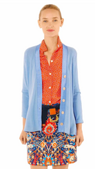 Woman wearing a blue cardigan over a patterned shirt and skirt on a white background