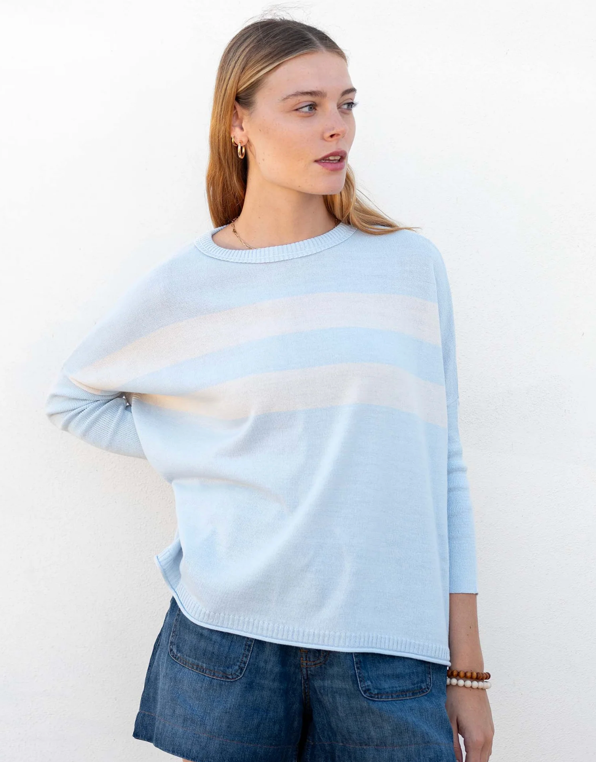 Woman wearing a light blue sweater with a white stripe on a white background