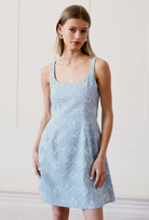 Woman wearing a light blue dress with floral pattern against a white background