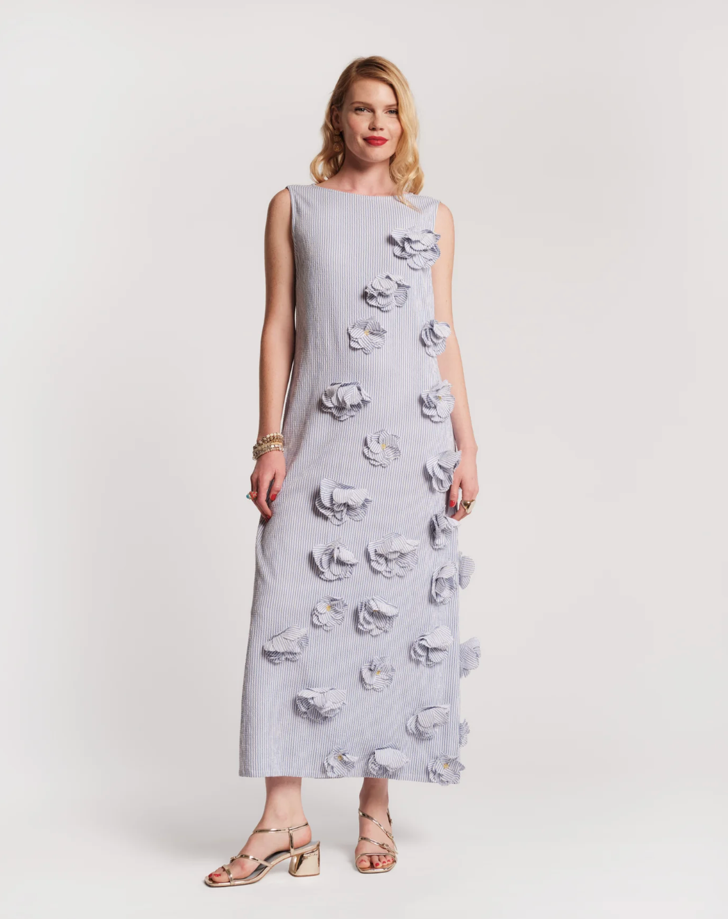 Woman wearing a light gray dress with floral patterns on a white background
