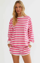 A woman modeling a pink and white horizontally striped long-sleeve top and matching shorts against a plain light background.