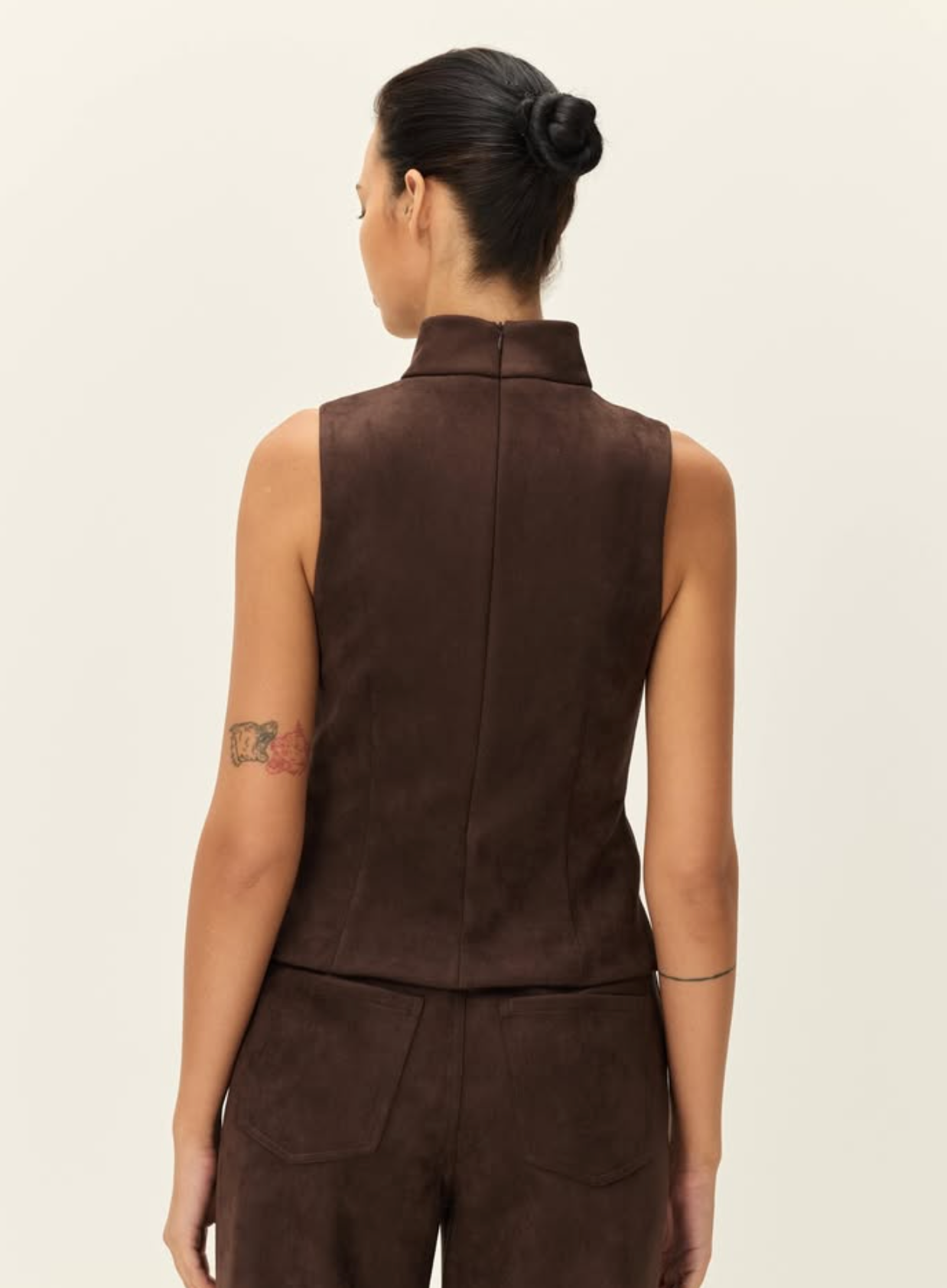 A model shown from the back wearing a sleeveless dark brown vest and matching dark brown pants against a plain off-white background.