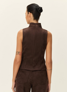 A model shown from the back wearing a sleeveless dark brown vest and matching dark brown pants against a plain off-white background.