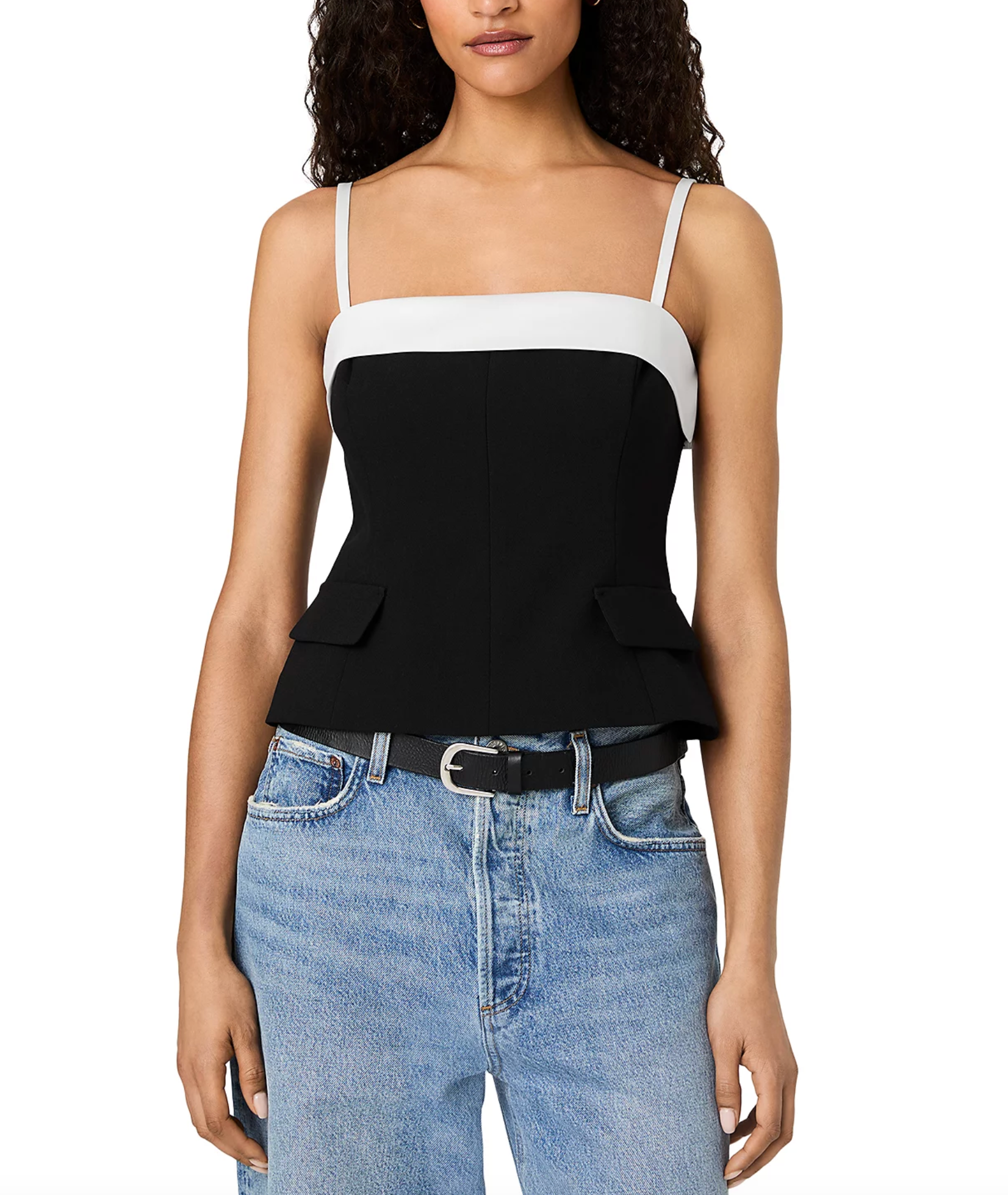 A woman wearing a color-blocked camisole top with a black and white design, paired with light-wash blue jeans and a black belt, against a plain white background.