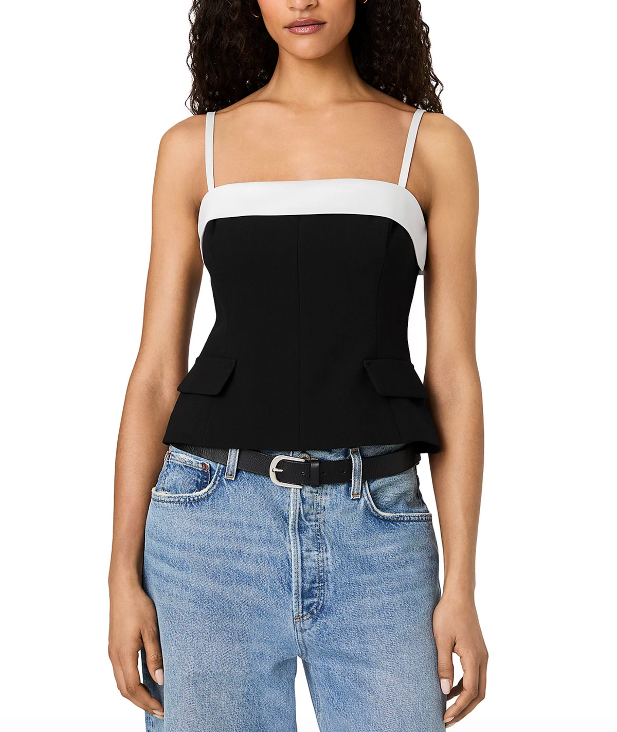 A woman wearing a color-blocked camisole top with a black and white design, paired with light-wash blue jeans and a black belt, against a plain white background.