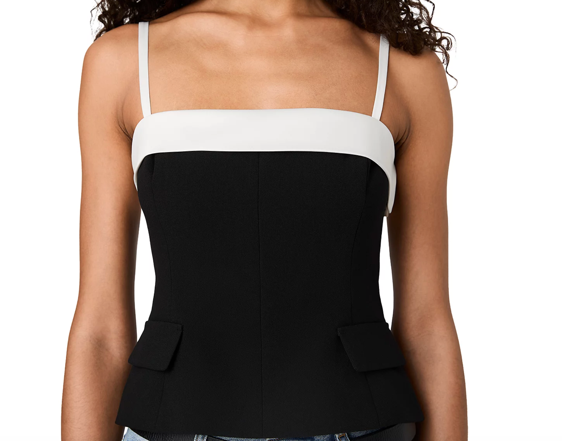 A woman wearing a color-blocked camisole top with a wide white band and thin white straps, paired with a structured black corset-style bodice and flap pockets.