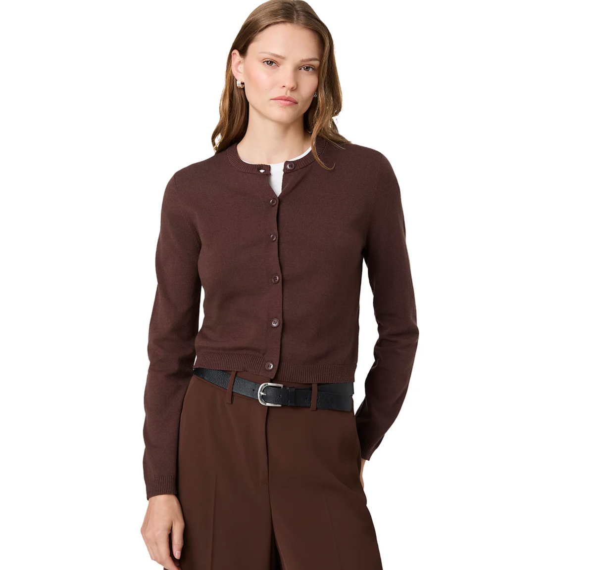 A woman modeling a dark brown button-front cardigan sweater over a white top, paired with brown trousers and a black belt, against a solid white background.