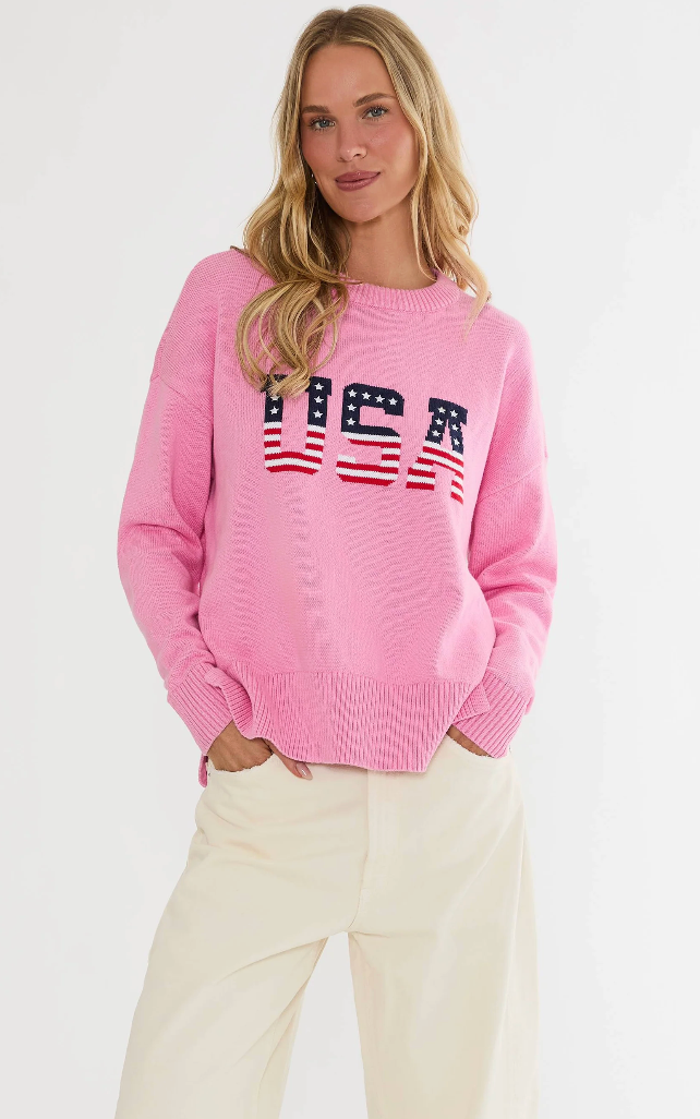 Woman wearing a pink sweater with 'USA' print on a white background