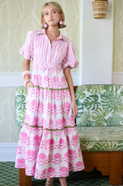 Woman wearing a pink dress with floral pattern in a room with green and white decor.