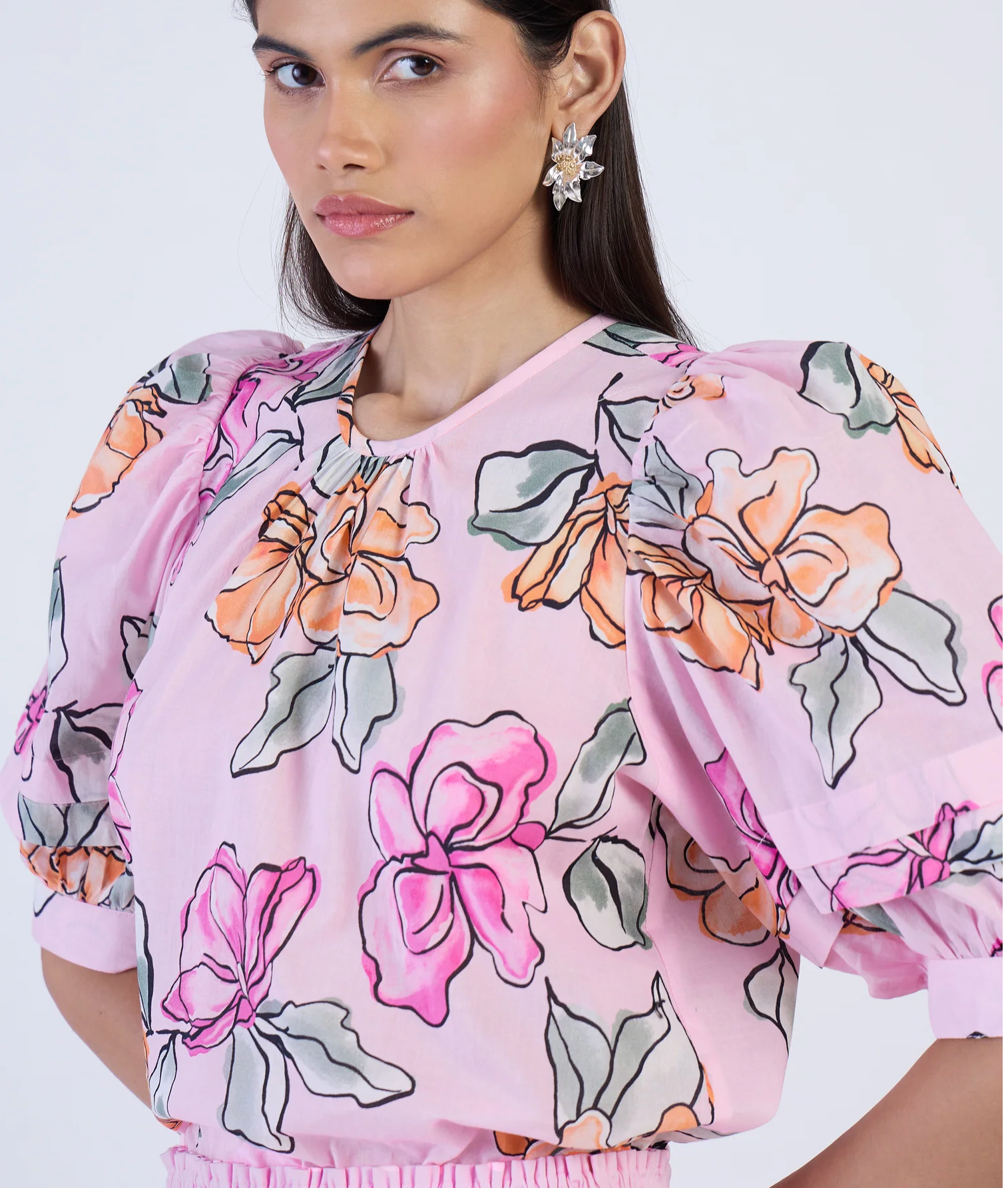 Woman wearing a pink floral blouse against a white background