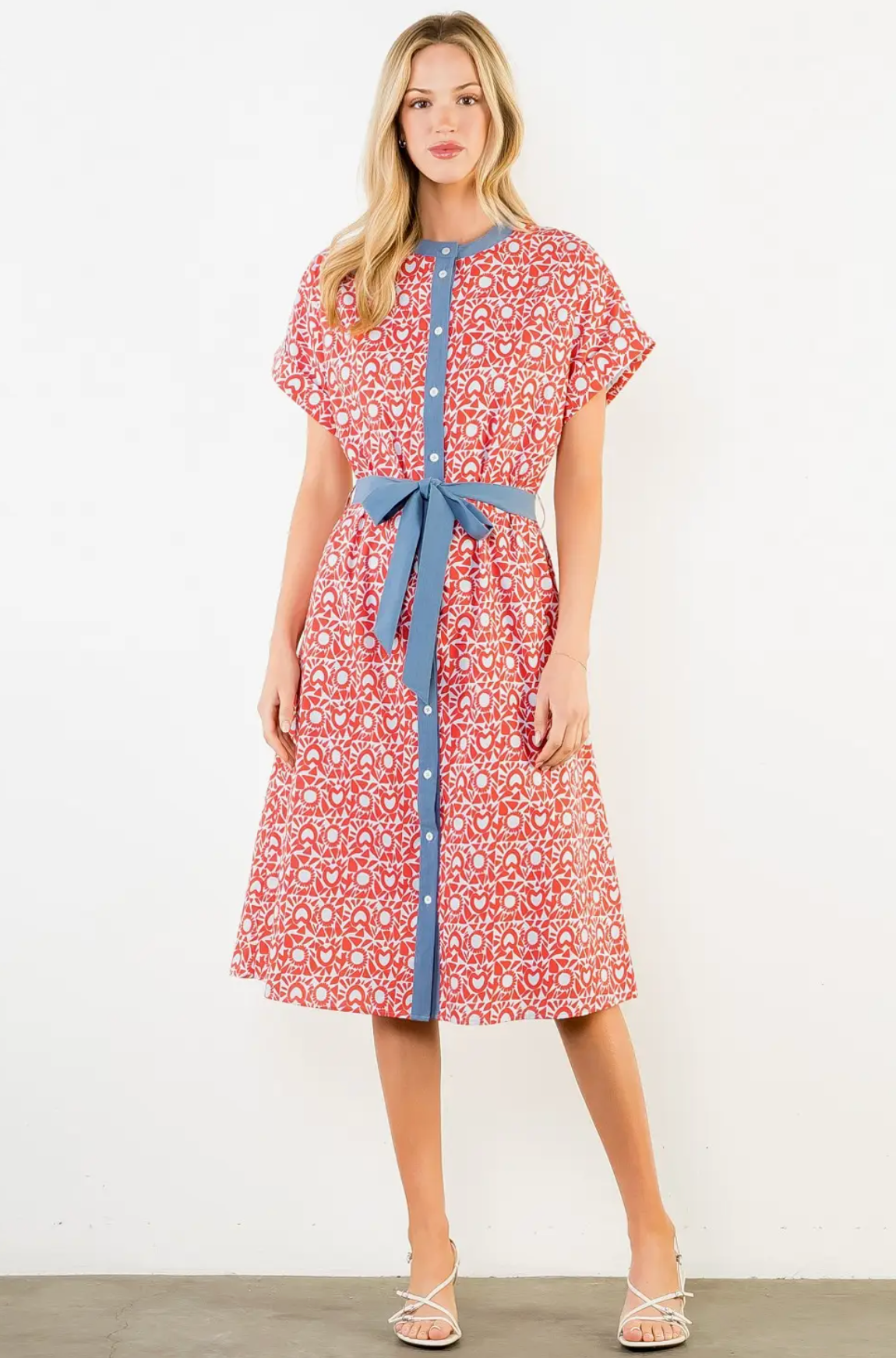 Woman wearing a red floral dress with a blue belt against a white background
