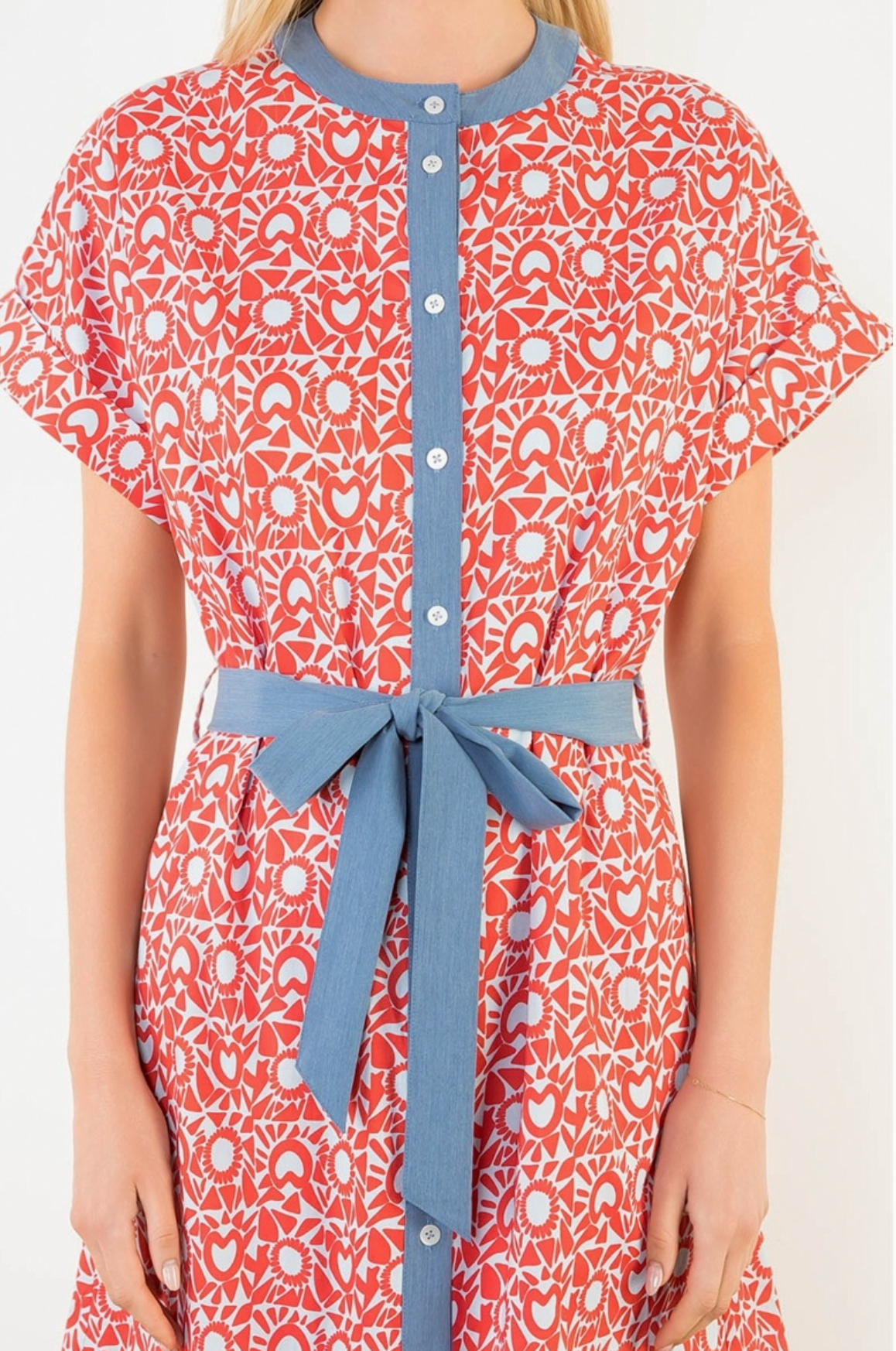 Red patterned dress with blue accents worn by a person on a white background