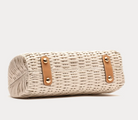Woven handbag with leather straps on a white background