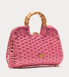 Pink woven handbag with bamboo handle on a light gray background