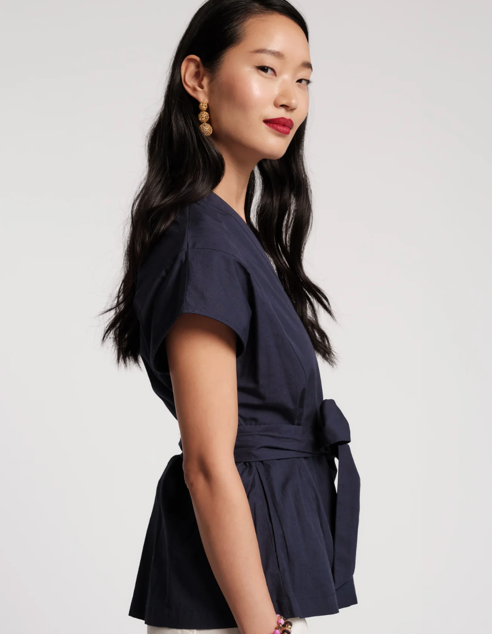 Woman wearing a navy blue wrap dress against a white background