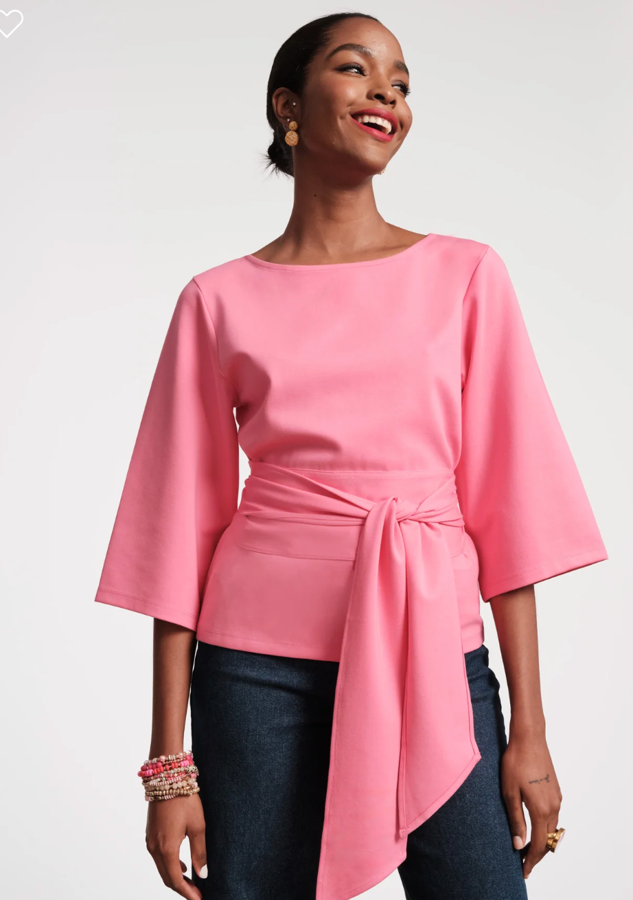 Woman wearing a pink blouse with a tie waist on a white background