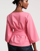 Pink wrap top worn by a person on a white background