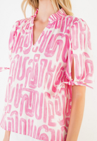 Woman wearing a pink and white patterned blouse on a white background