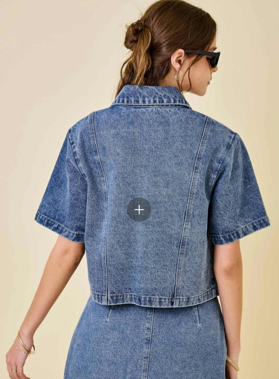 Person wearing a blue denim jacket with a visible brand logo on a beige background