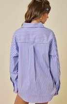 Woman wearing a blue and white striped shirt against a beige background