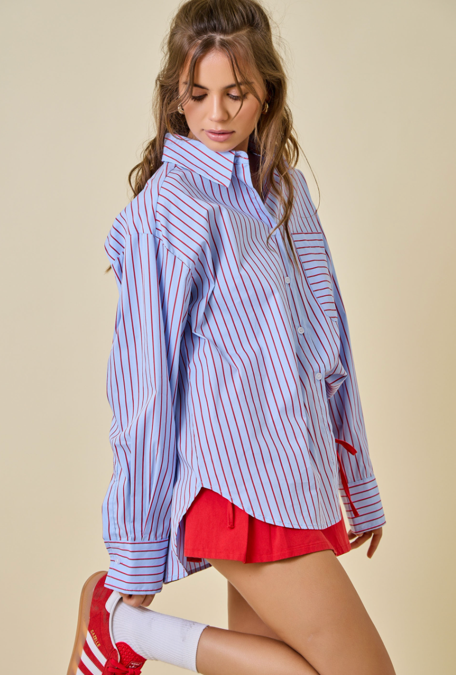 Woman wearing a striped shirt and red shorts on a beige background