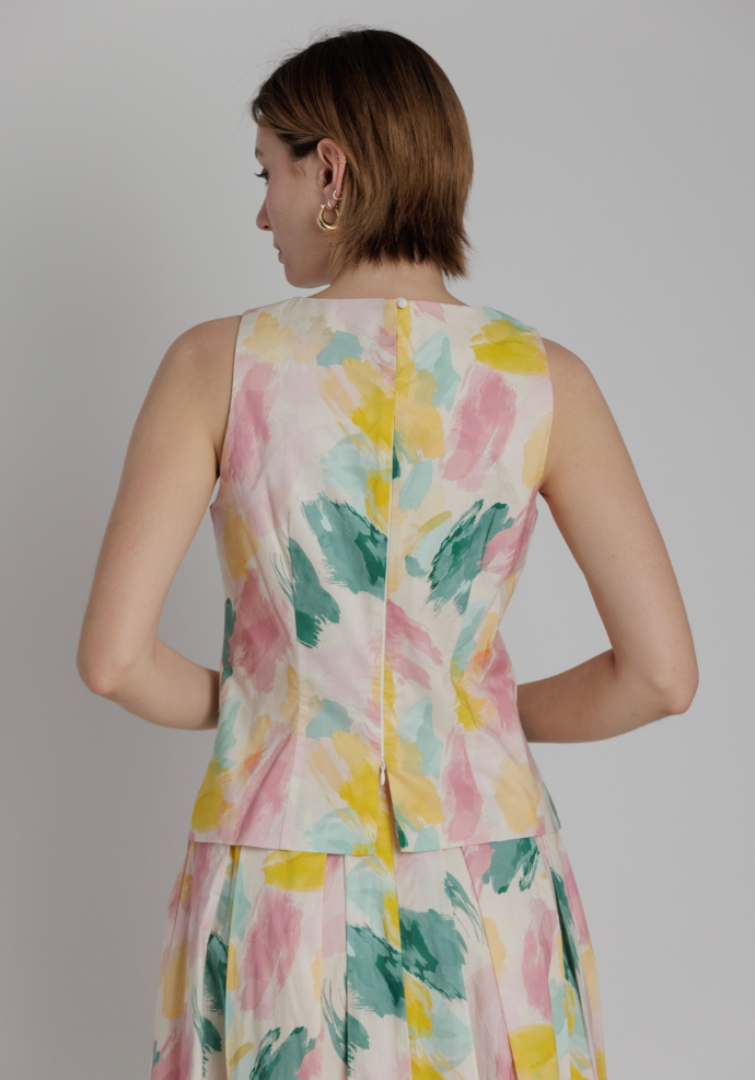 Woman wearing a sleeveless dress with a floral pattern on a plain background