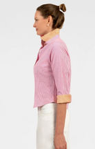 Woman wearing a pink striped shirt with a yellow collar against a white background