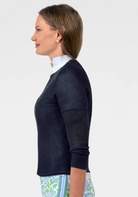 Woman wearing a navy sweater over a white shirt with a light-colored background
