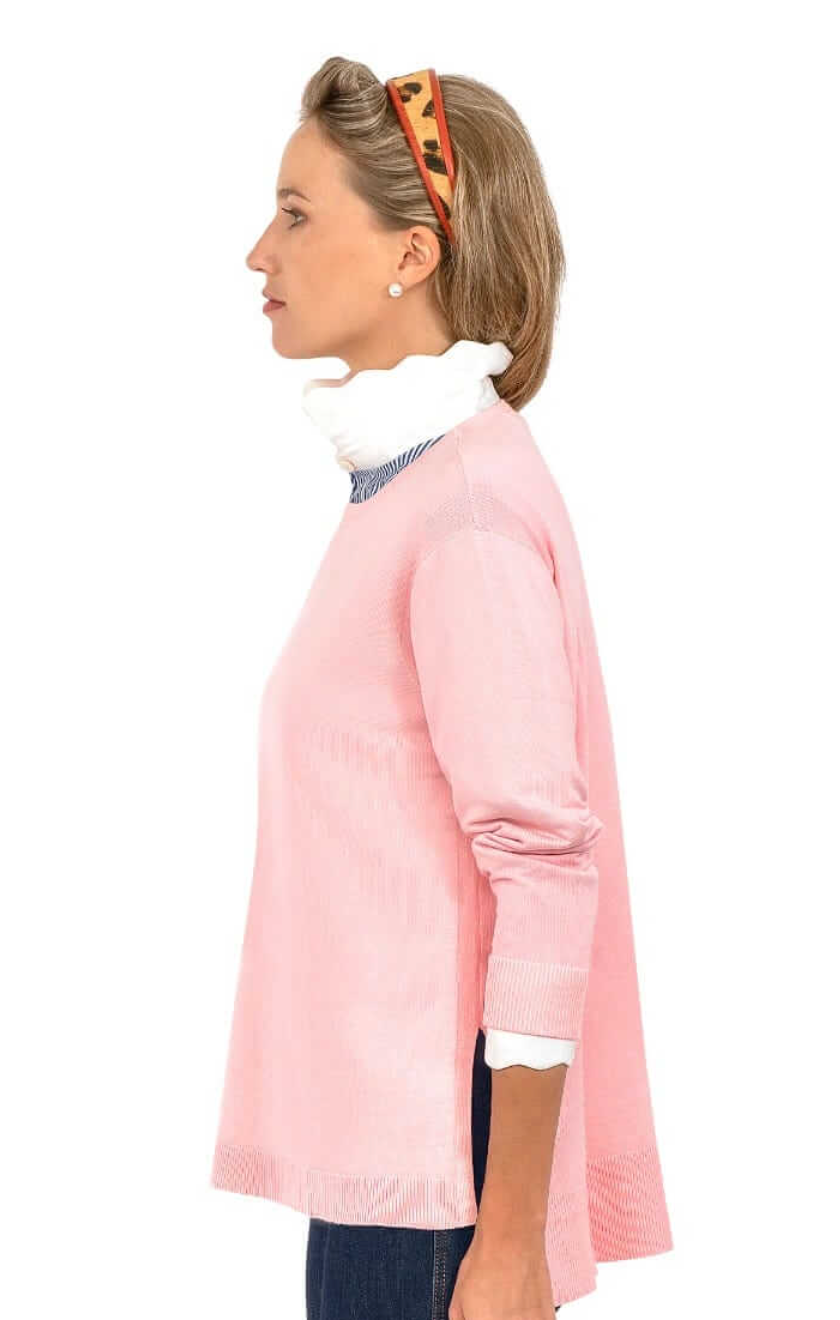 Woman wearing a pink cardigan over a white shirt with a white background