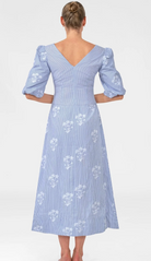 Woman wearing a blue dress with white floral patterns on a white background