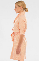 Woman wearing a peach-colored striped dress on a white background