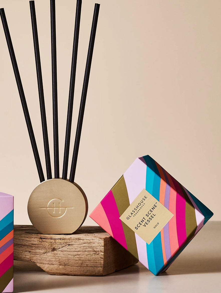 Decorative diffuser with black sticks and a colorful box on a beige background