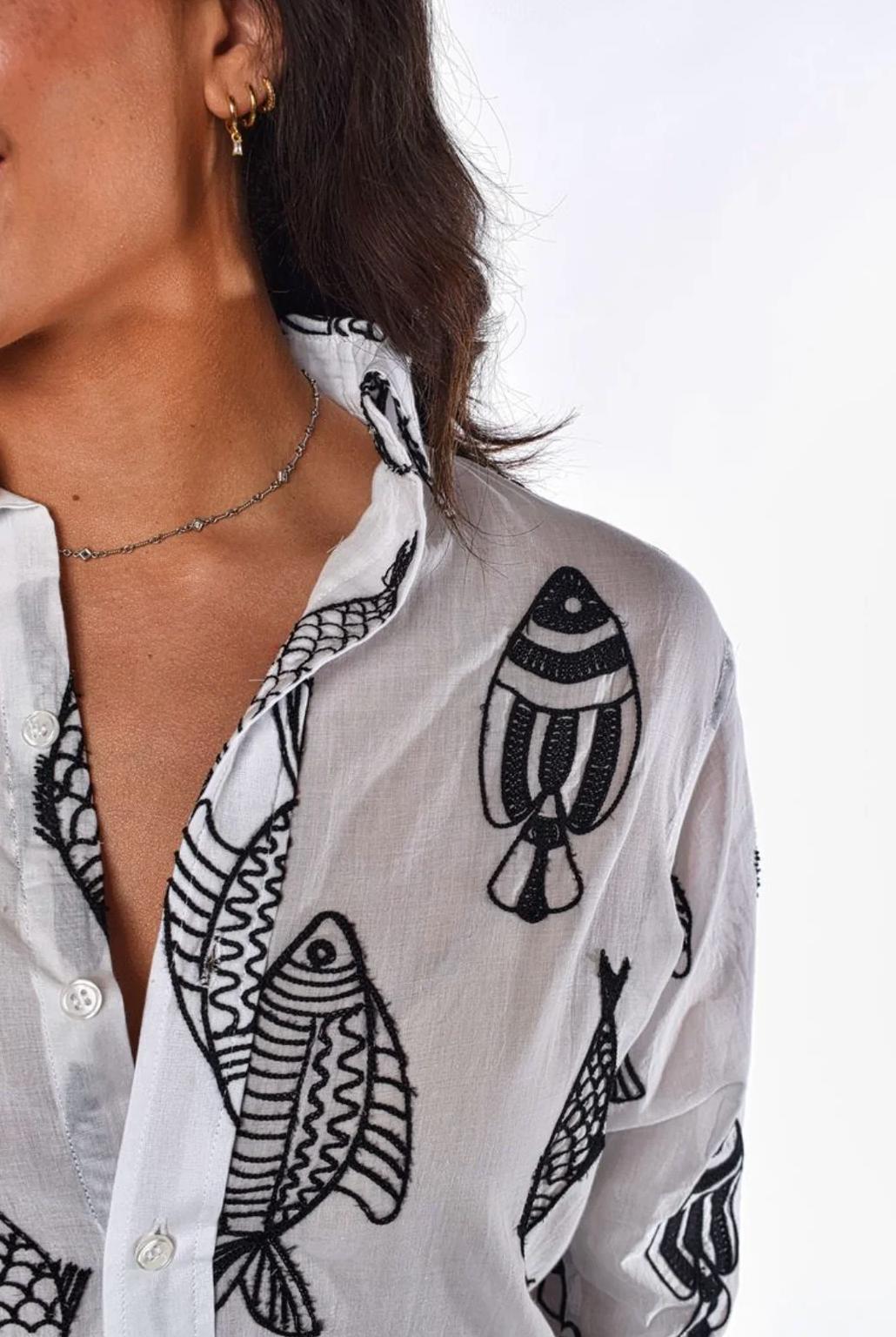 White shirt with black fish patterns worn by a person on a white background