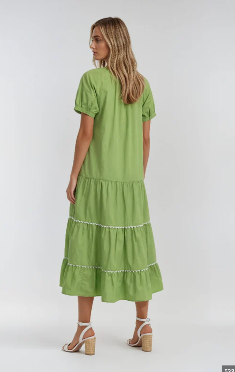 Woman wearing a green dress with ruffled layers on a white background