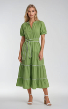 Woman wearing a green dress with white embellishments on a white background