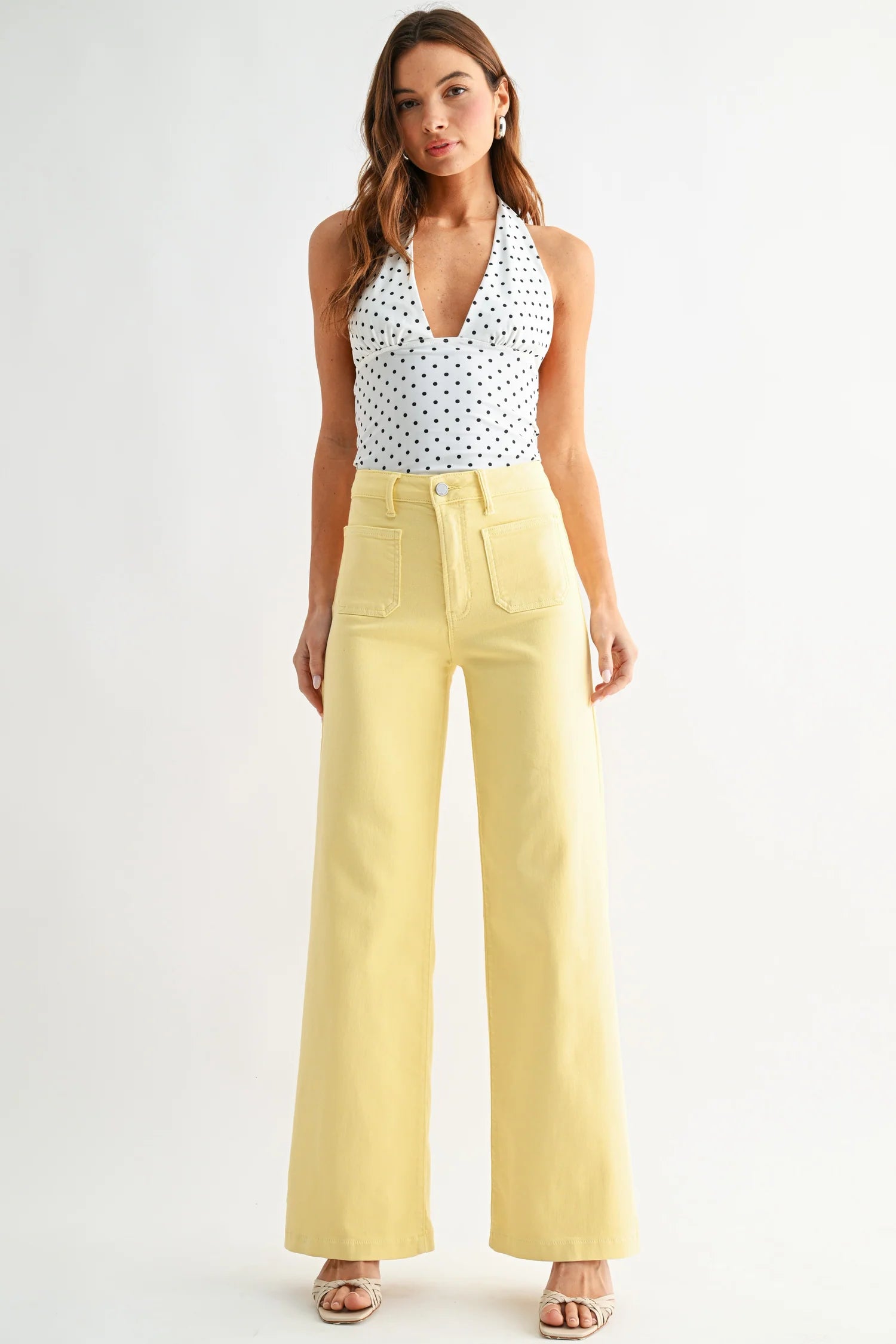 Woman wearing a polka dot top and yellow pants on a white background