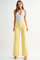 Woman wearing a polka dot top and yellow pants on a white background