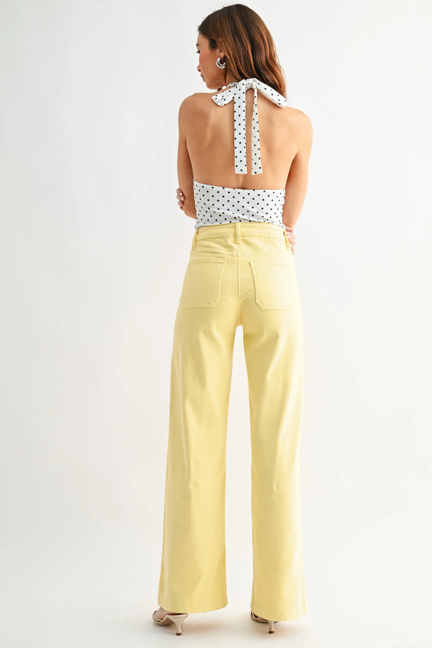 Woman wearing a polka dot top and yellow pants on a white background