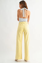 Woman wearing a polka dot top and yellow pants on a white background