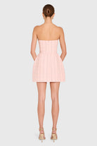 Woman wearing a pink strapless dress on a white background