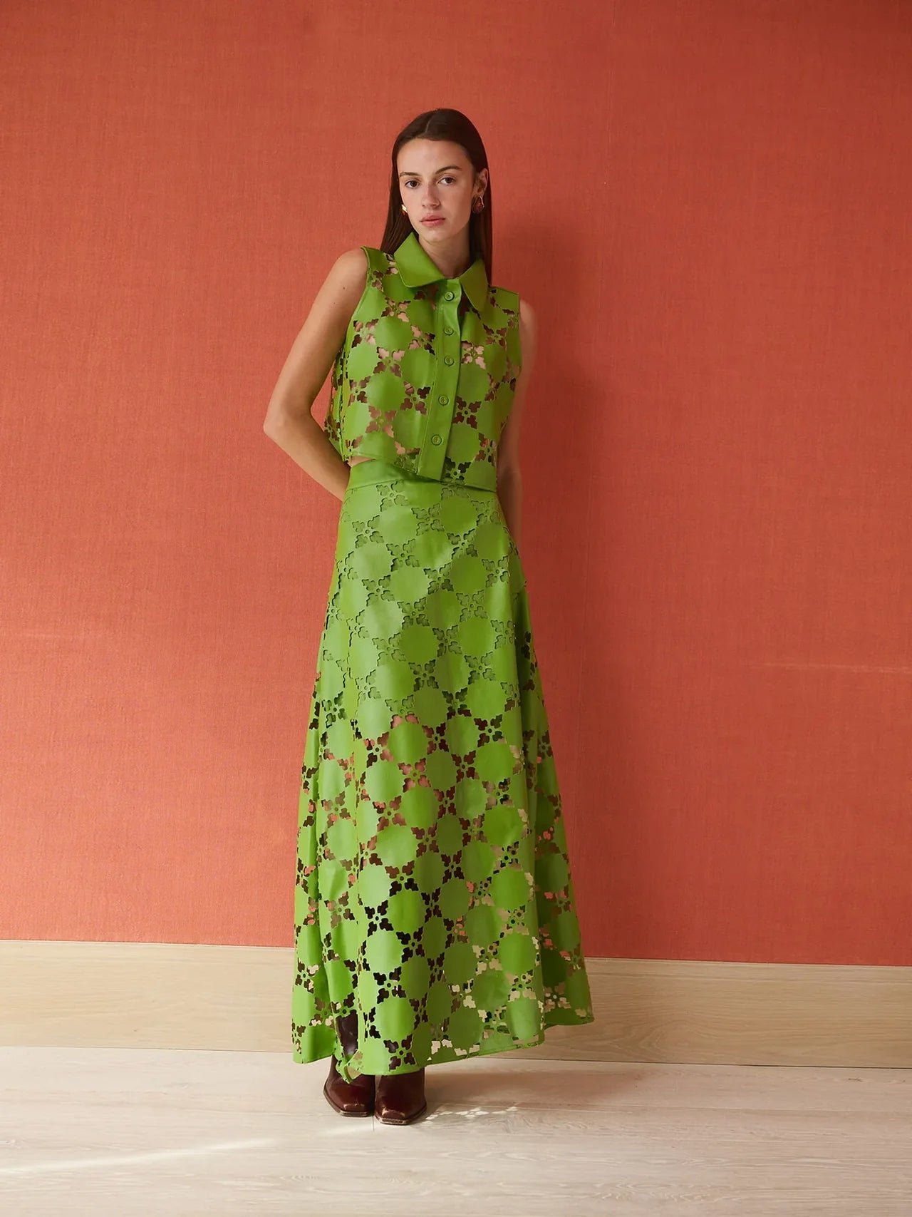 Woman wearing a green faux leather cut matching set against a red wall