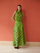 Woman wearing a green faux leather cut matching set against a red wall