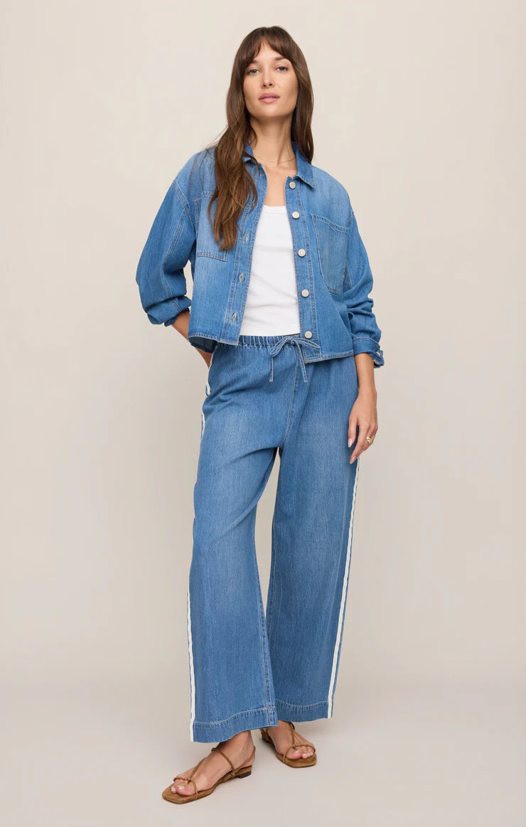 Woman wearing a blue denim jacket and jeans on a beige background