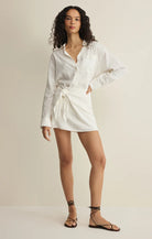 Woman wearing a white shirt dress against a plain background
